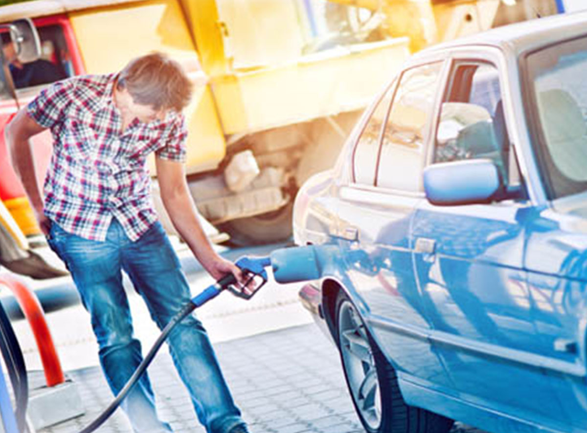 man pumping gas into blue vehicle