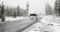 image of SUV traveling on the road while it snows