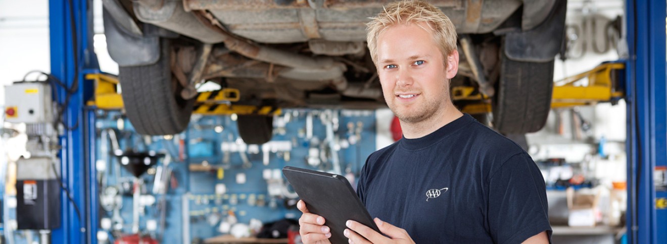 mechanic standing by automobile on a hydraulic lift