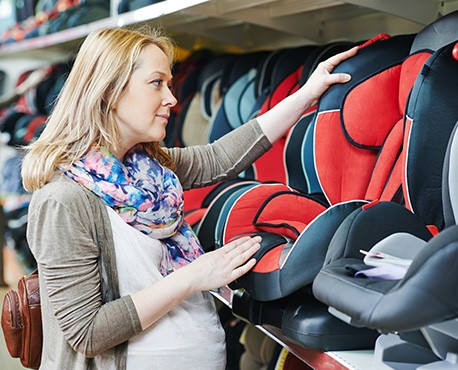Pregnant woman inspecting a car seat while shopping